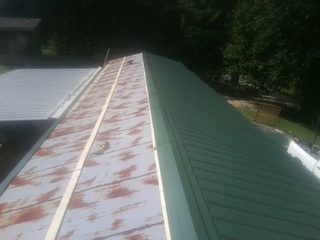 Old rusted panels beside newly installed green metal roofing — Wind Damage Roof Repair by Roofing Brothers in North Las Vegas