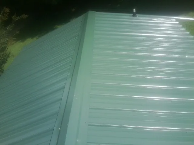 New green metal panels meeting at the ridge of a roof — Flat Roof Repair work by our crew in North Las Vegas
