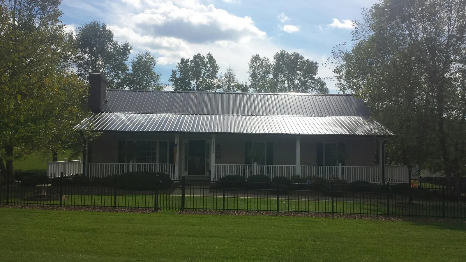 Gray metal roof on a brick ranch with a full width front porch — Gutter Guard Installation work by our crew in North Las Vegas