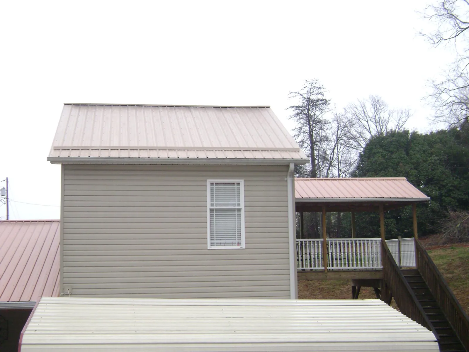 Tan metal roofs on a two story addition and attached porch, from a Roof Replacement job in North Las Vegas