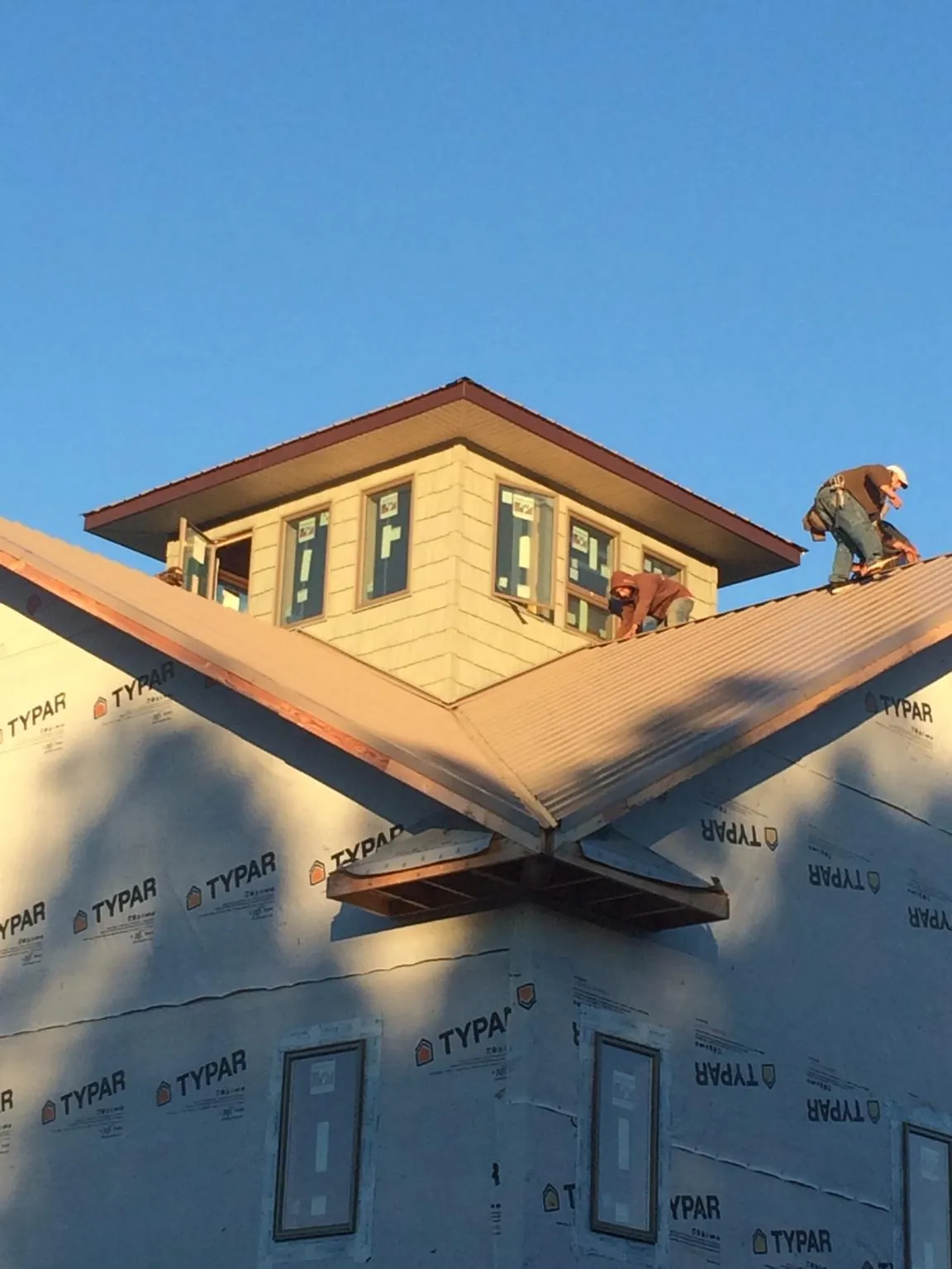 Roofers working around a rooftop cupola on a new metal roof at sunset — Roof Waterproofing in North Las Vegas by Roofing Brothers